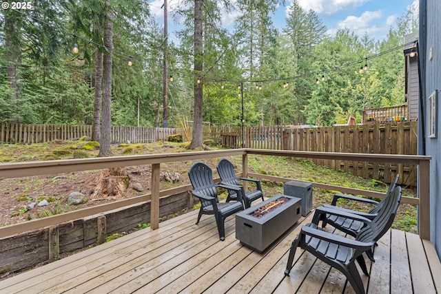 wooden deck with a fire pit and a fenced backyard
