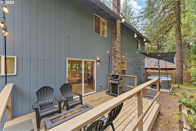 deck with a hot tub, a fire pit, and grilling area