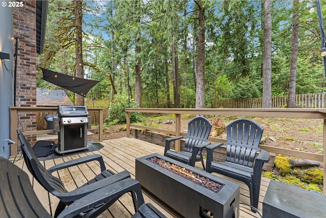 deck featuring grilling area, fence, and a fire pit