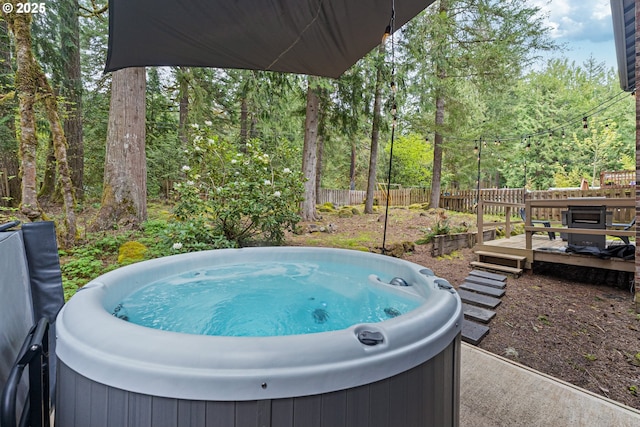 exterior space featuring a hot tub, a forest view, fence, and a wooden deck