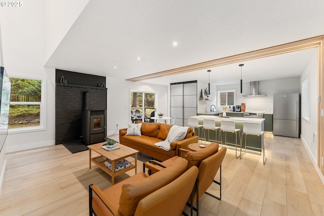 living area featuring a healthy amount of sunlight, baseboards, light wood-type flooring, and recessed lighting