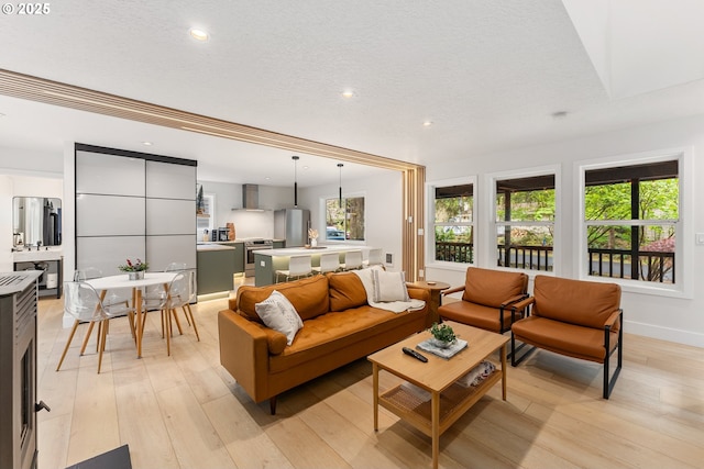 living room featuring recessed lighting, baseboards, light wood finished floors, and a textured ceiling