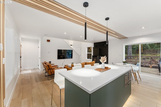 kitchen featuring light countertops, light wood-style flooring, recessed lighting, a kitchen island, and green cabinets