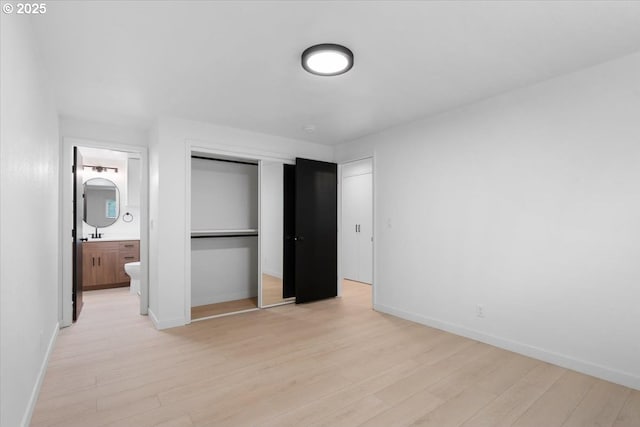 unfurnished bedroom with light wood-style floors, baseboards, and a closet