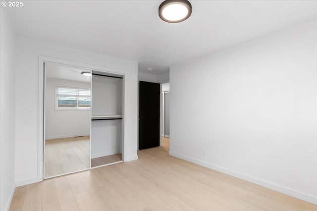 unfurnished bedroom featuring light wood-type flooring, a closet, and baseboards