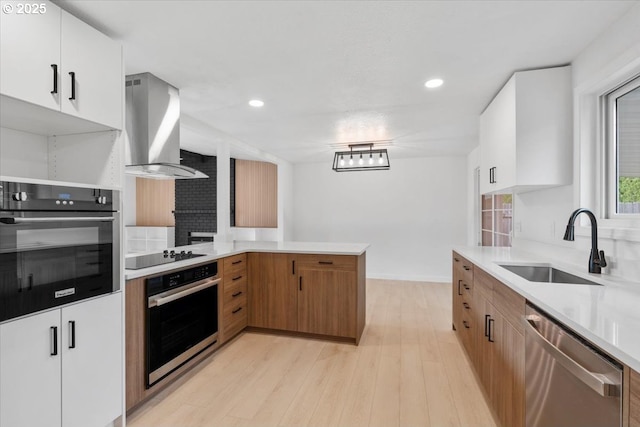 kitchen featuring appliances with stainless steel finishes, range hood, a sink, light wood finished floors, and light countertops
