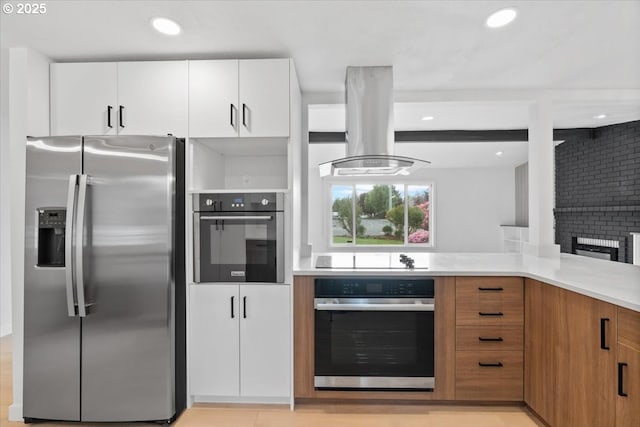 kitchen featuring stainless steel appliances, island exhaust hood, light countertops, brown cabinetry, and white cabinetry