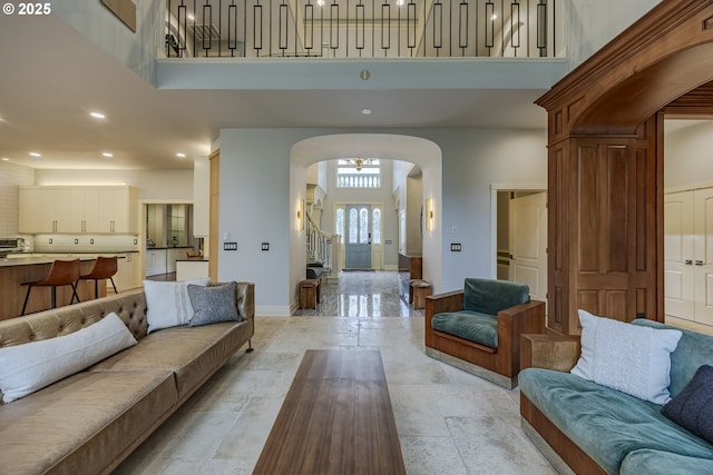 1564 Regency Dr, Eugene, OR 97401 - living room with a towering ceiling, arched walkways, stone tile flooring, baseboards, and recessed lighting