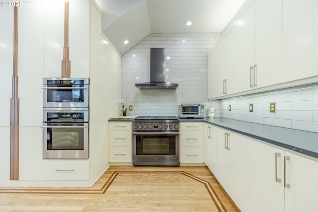 1564 Regency Dr, Eugene, OR 97401 - kitchen featuring appliances with stainless steel finishes, exhaust hood, tasteful backsplash, light wood-type flooring, and dark countertops