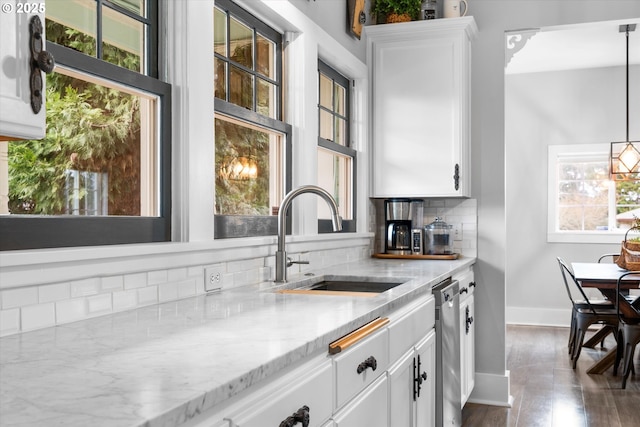 kitchen featuring dishwasher, tasteful backsplash, a sink, and white cabinets