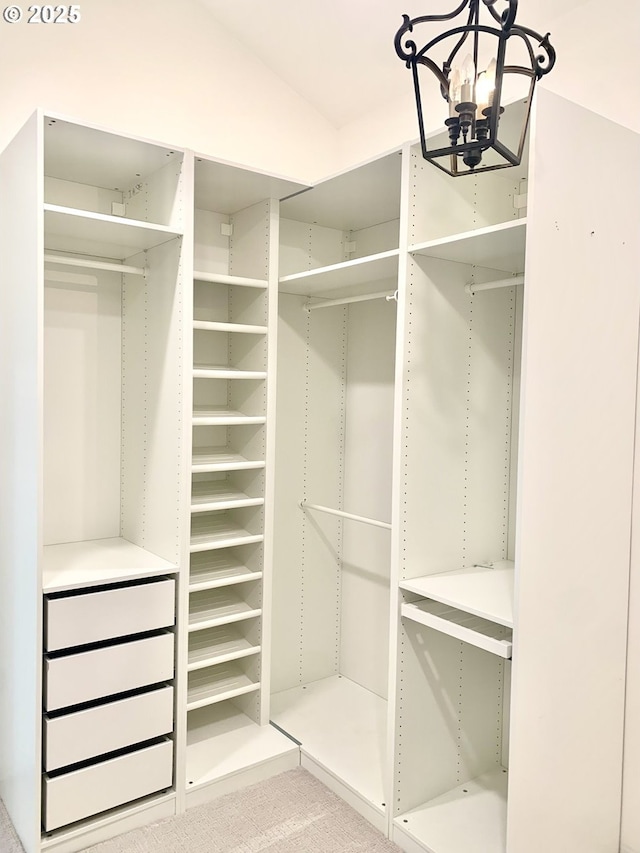 walk in closet featuring vaulted ceiling and an inviting chandelier