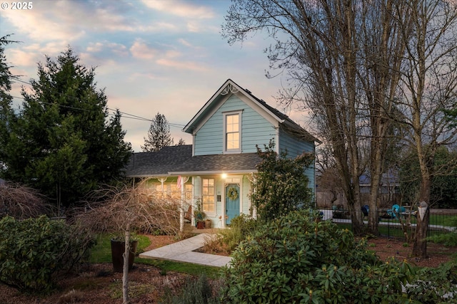 view of front of property with a shingled roof and fence