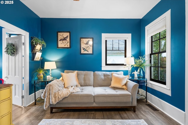 living room with baseboards, visible vents, and wood finished floors