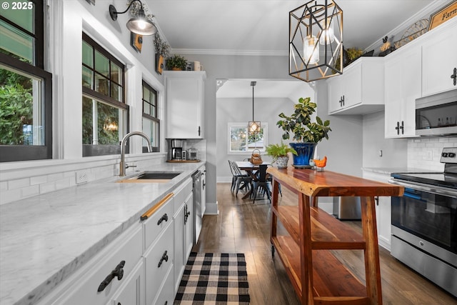 kitchen with a chandelier, stainless steel appliances, a sink, light stone countertops, and crown molding