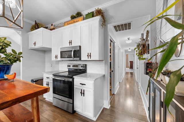 kitchen with visible vents, dark wood finished floors, stainless steel appliances, crown molding, and backsplash