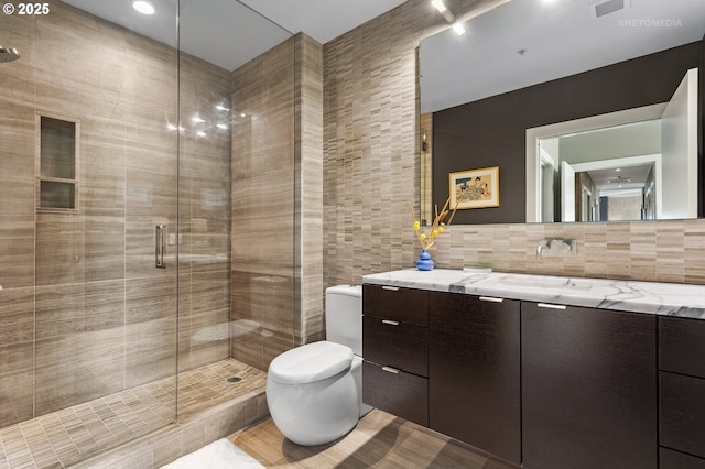 bathroom with tasteful backsplash, tile walls, vanity, an enclosed shower, and toilet