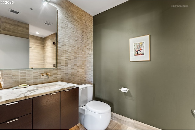 bathroom featuring tile walls, vanity, tasteful backsplash, and toilet