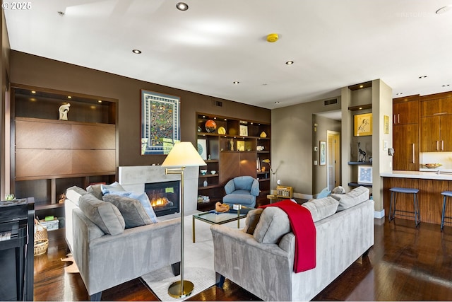 living room featuring dark wood-type flooring and built in features