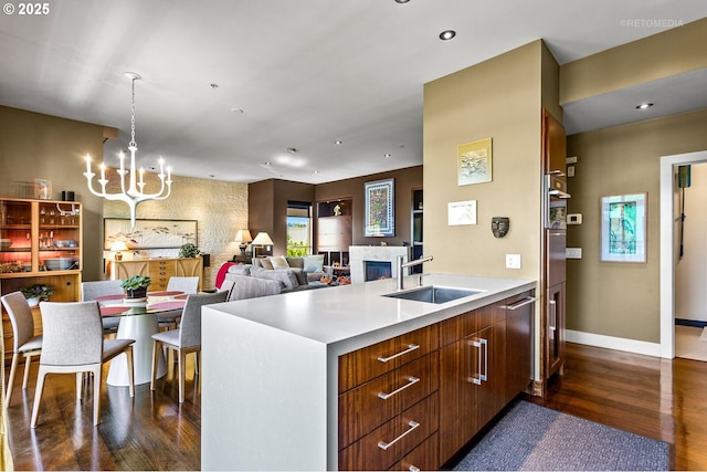 kitchen featuring sink, a notable chandelier, dark hardwood / wood-style floors, and a center island with sink