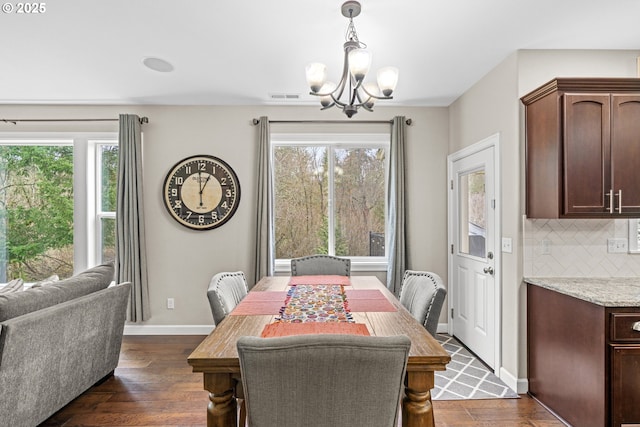 dining area with dark wood-style floors, baseboards, visible vents, and a chandelier