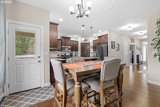 dining area with recessed lighting, baseboards, an inviting chandelier, and dark wood-style flooring