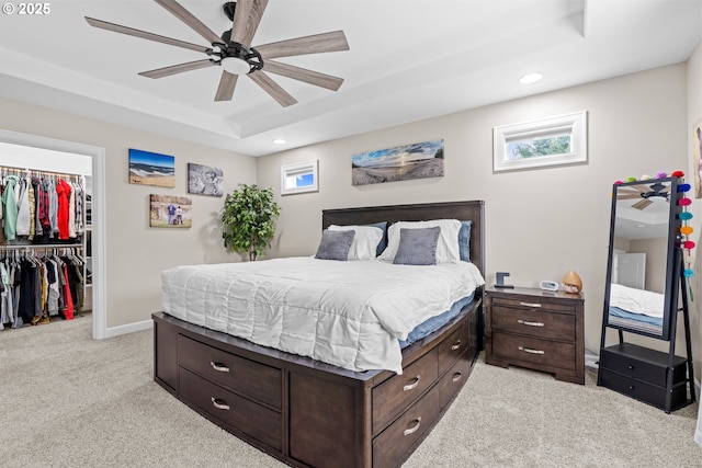 bedroom featuring light carpet, a tray ceiling, recessed lighting, a closet, and a spacious closet