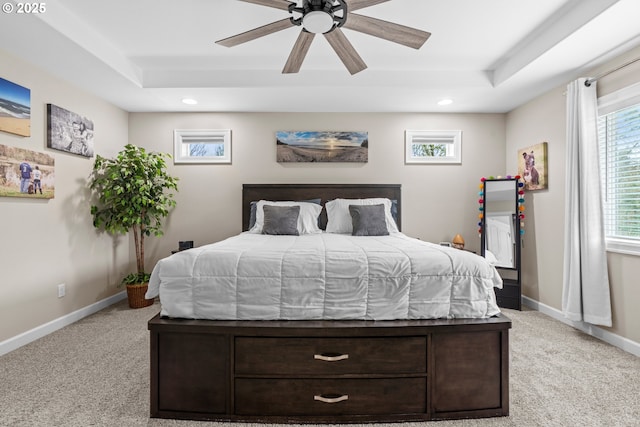 bedroom with baseboards, a raised ceiling, and light colored carpet