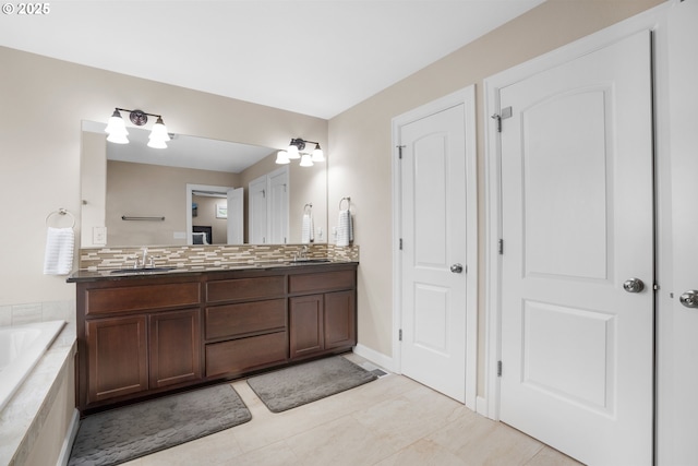 bathroom featuring double vanity, decorative backsplash, a bath, and a sink