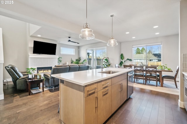 kitchen featuring dark wood-type flooring, sink, light brown cabinets, dishwasher, and a kitchen island with sink