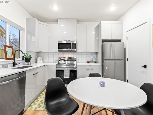 kitchen with a kitchen breakfast bar, sink, decorative backsplash, white cabinetry, and stainless steel appliances