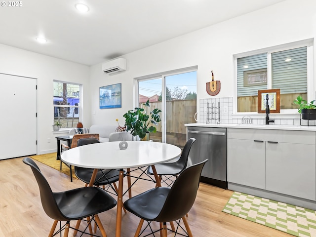 dining area featuring light hardwood / wood-style floors, an AC wall unit, and sink