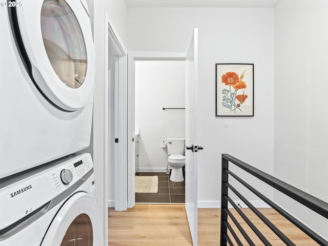 laundry area with hardwood / wood-style floors and stacked washer / dryer