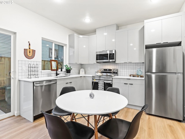 kitchen featuring white cabinets, sink, stainless steel appliances, and light hardwood / wood-style flooring