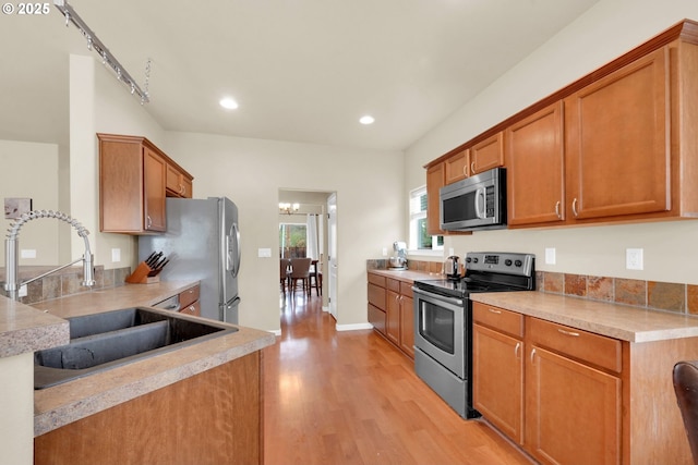 kitchen with appliances with stainless steel finishes, sink, and light hardwood / wood-style floors