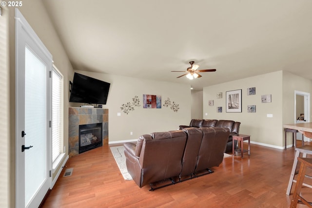 living room featuring ceiling fan, a fireplace, and light hardwood / wood-style floors