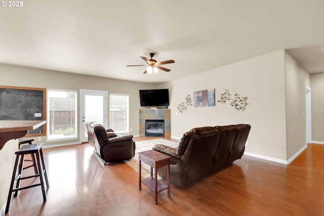 living room with a tiled fireplace, hardwood / wood-style floors, and ceiling fan