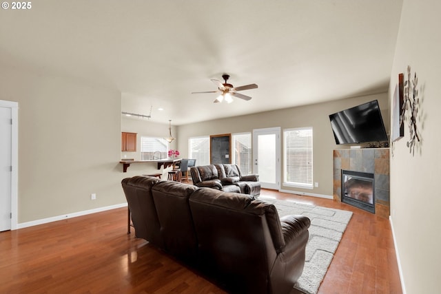 living room featuring a tiled fireplace, sink, hardwood / wood-style flooring, and ceiling fan