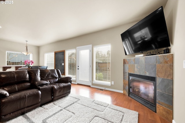 living room with a tiled fireplace and wood-type flooring