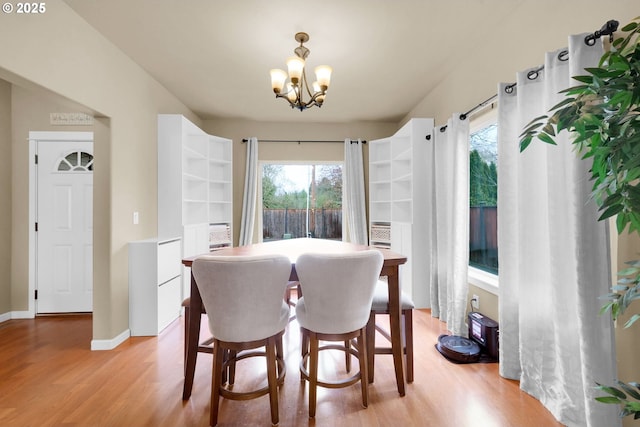 dining space with plenty of natural light, light wood-type flooring, and a notable chandelier