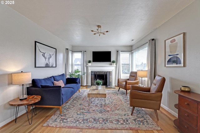 living room with light wood-type flooring, plenty of natural light, baseboards, and a fireplace