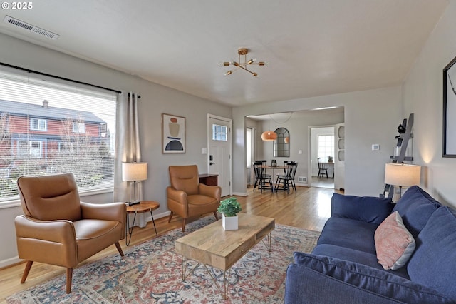 living area featuring visible vents, baseboards, and wood finished floors