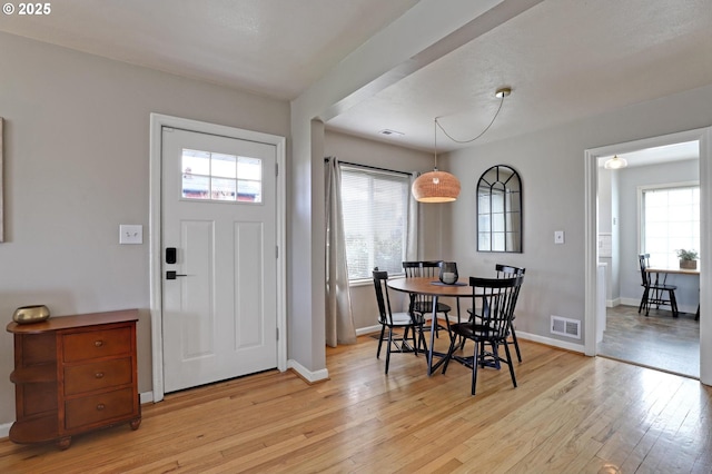 dining space with light wood-style floors, visible vents, and baseboards