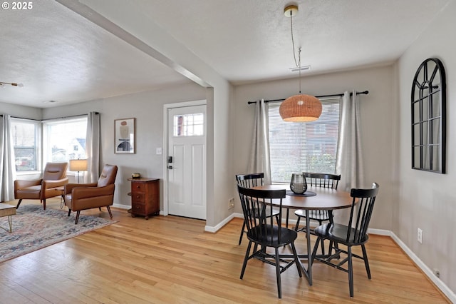 dining space featuring a textured ceiling, baseboards, plenty of natural light, and light wood finished floors