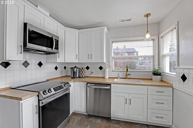 kitchen with a sink, stainless steel appliances, white cabinets, and light countertops