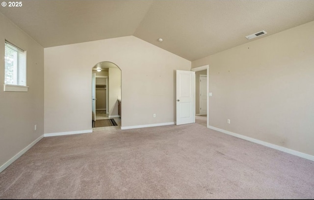 carpeted spare room with vaulted ceiling