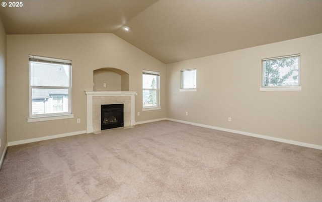 unfurnished living room featuring a wealth of natural light, a tile fireplace, and vaulted ceiling