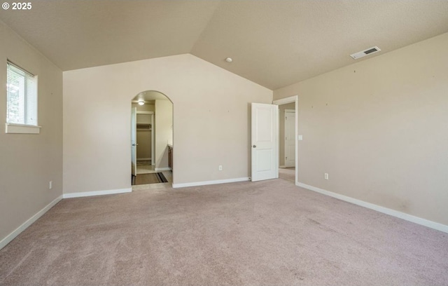 empty room with vaulted ceiling and light carpet