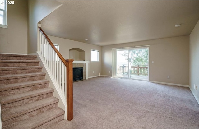 unfurnished living room featuring light carpet and a tiled fireplace