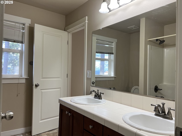 bathroom featuring vanity, a shower, and a wealth of natural light