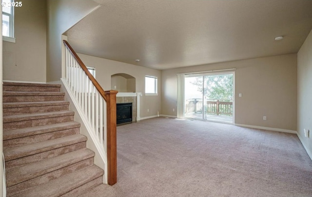 unfurnished living room featuring a tiled fireplace and light carpet